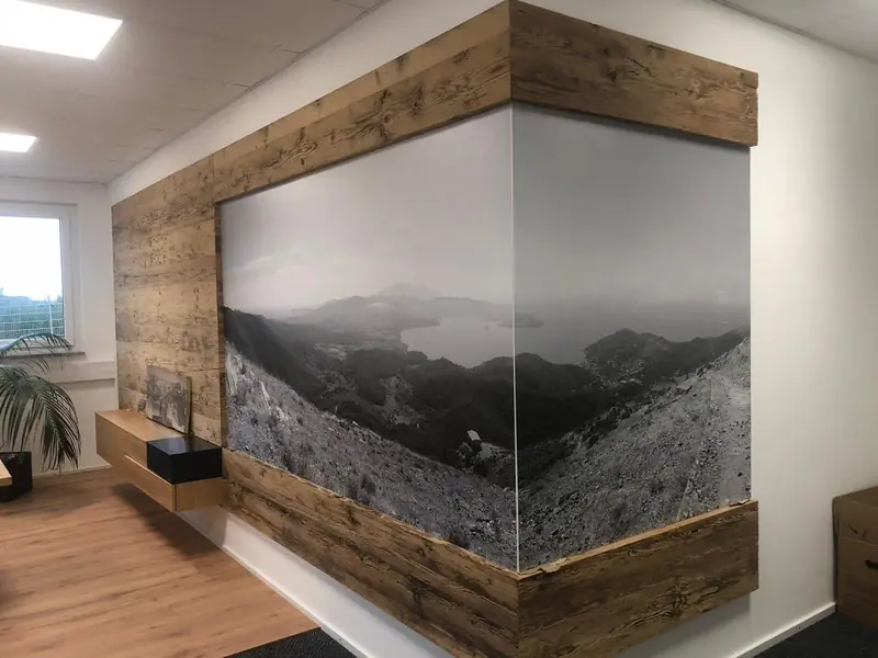 Büro mit Wandverkleidung aus Holz um eine große Bildfläche, Möbel aus Holz davor