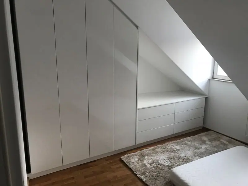 Weißer Einbauschrank mit Schrägfläche unter einer Dachschräge